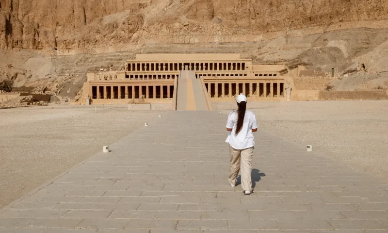 Una mujer de espaldas a la cámara caminando hacia el Templo de Hatshepsut, Deir El Bahari.