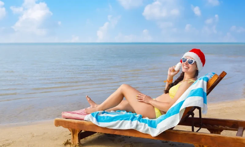 Joven sonriente con gorro de Papá Noel y gafas de sol, tumbada en una hamaca, navidad en egipto