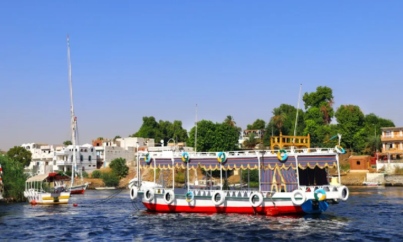 Barco turístico colorido y casas tradicionales en un pueblo nubio de la isla Elefantina, río Nilo, Asuán, Egipto, pueblo nubio