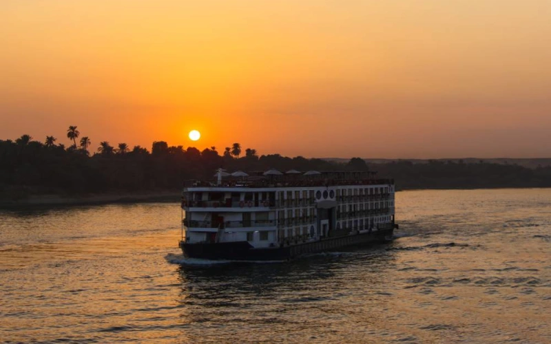 Nile cruise ship sailing past palm-lined banks at sunset on the Solar Eclipse Nile Cruise 2027