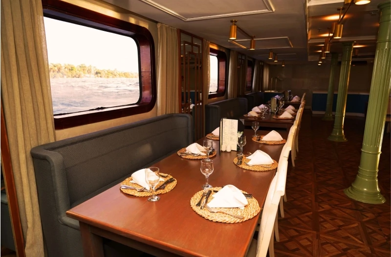 Restaurante panorámico del crucero por el Nilo Le Fayan II con mesas preparadas y vistas al río