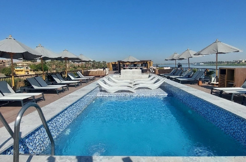 Piscina al aire libre en la cubierta del crucero Le Fayan II, con tumbonas y vistas al río Nilo