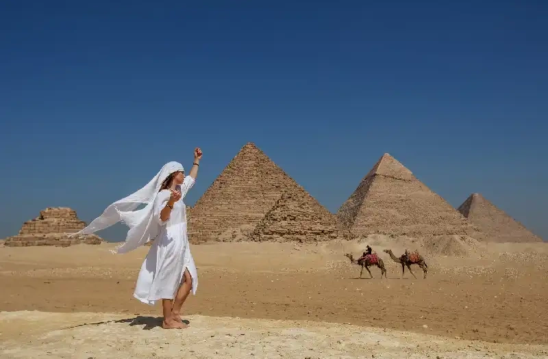 Offerte viaggi Pasqua Egitto, una donna indossa un vestito bianco davanti alle tre piramidi