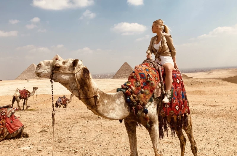Viaggio al Cairo, una donna alle piramidi a dorso di un cammello