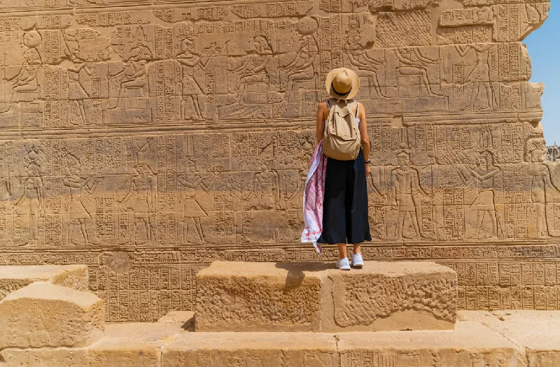 Mujer de pie frente al Templo de Filae, también conocido como Templo de Isis, en Asuán, Egipto.