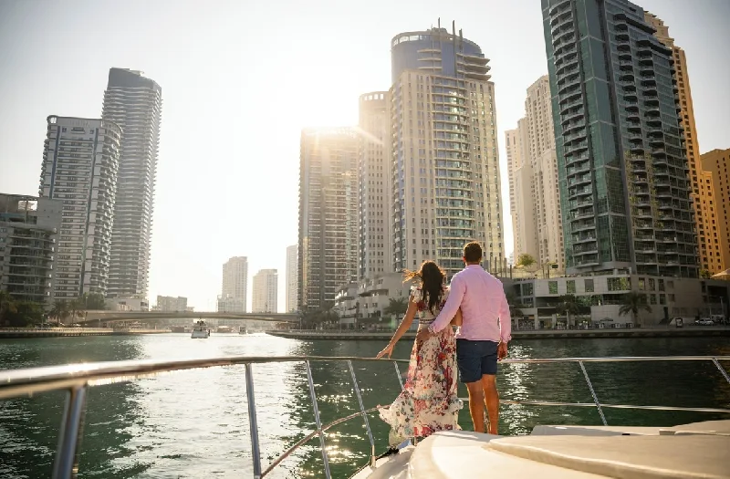 Un hombre y una mujer de vacaciones en los Emiratos Árabes Unidos, mirando hacia Dubai Marina al atardecer.