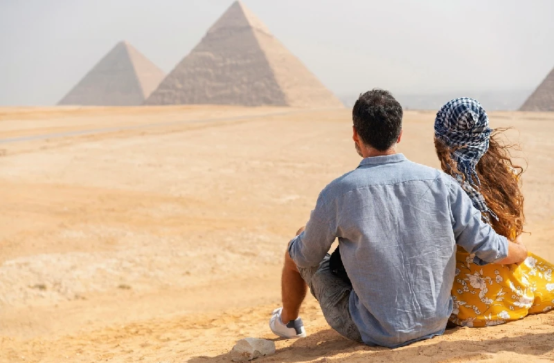 Vista trasera de una pareja que viaja visitando las Pirámides de Giza en Egipto.
