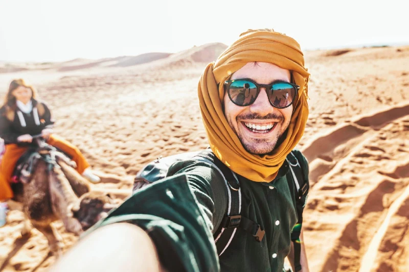 Turista feliz divirtiéndose disfrutando de un paseo en camello en grupo por el desierto