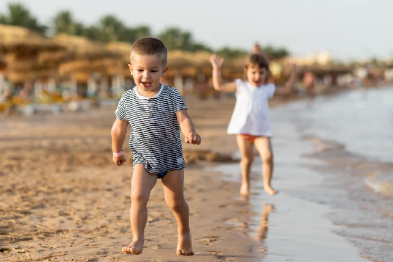 Niños hermosos divirtiéndose en una playa de arena. Disfrutando de un día soleado de verano, jugando y corriendo por la playa.