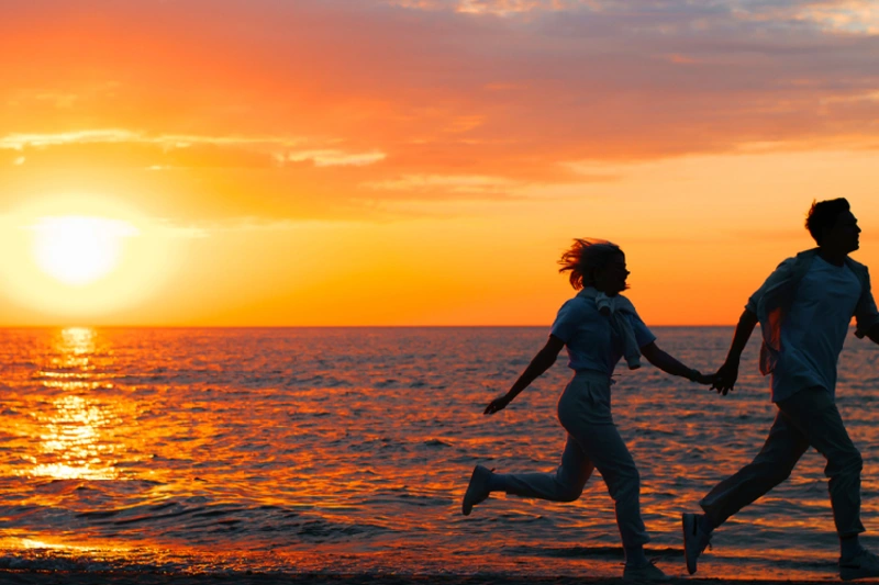 pareja corriendo en la playa al atardecer
