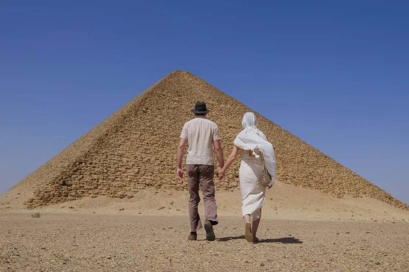 pareja sosteniendo las manos caminando hacia las Pirámides