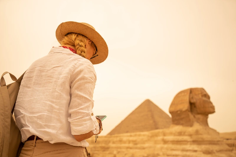 Mujer charlando por la pantalla adelante de Pirámides de Giza y gran Esfinage