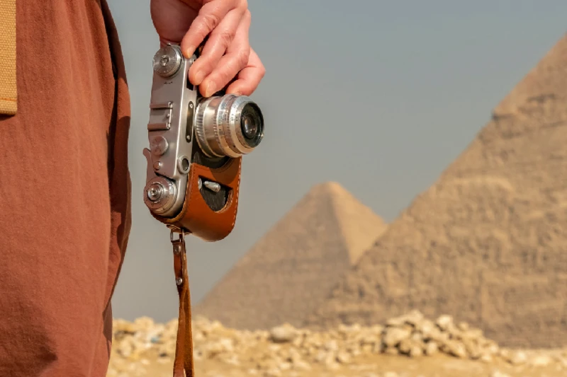uma mujer llevando su camera adelante de las Pirámides