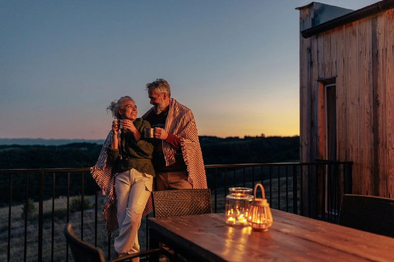 Pareja mayor disfrutando de una bebida en una terraza al atardecer
