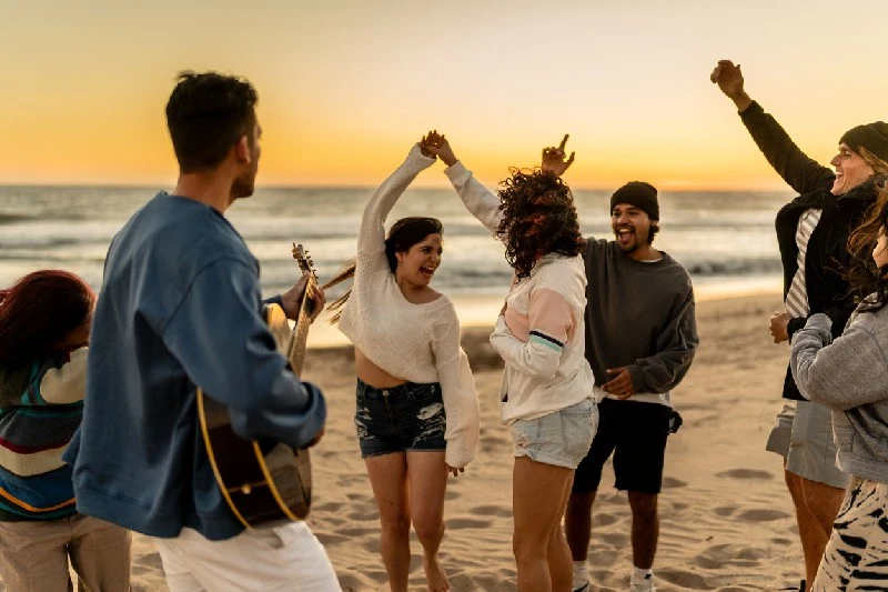 Grupo de amigos disfrutando en la playa al atardecer.