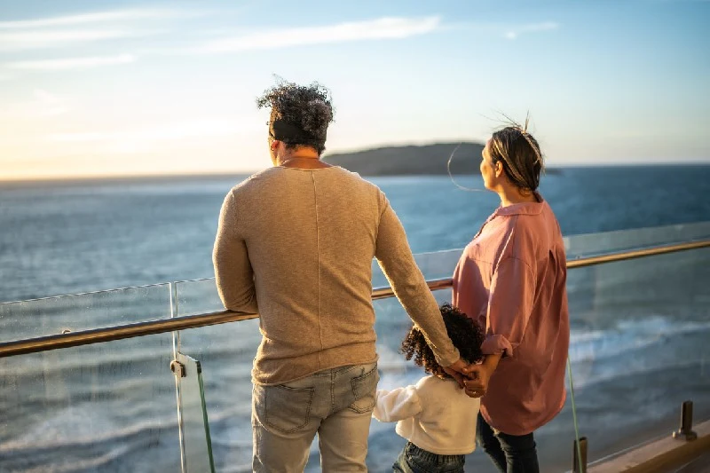 Familia mirando el océano desde un balcón con vista al mar.