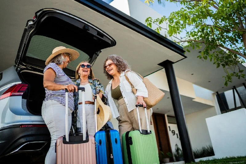 Grupo de amigas con maletas llegando a un alojamiento para sus vacaciones.