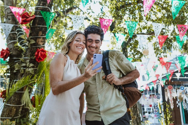 Pareja tomando una selfie en una celebración con decoraciones Mexicanas