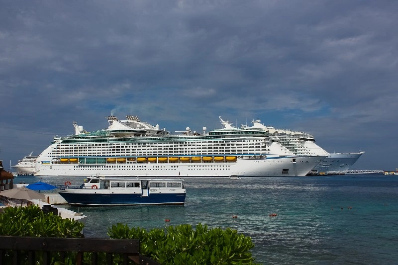 Crucero atracado en el puerto con un barco más pequeño en primer plano.