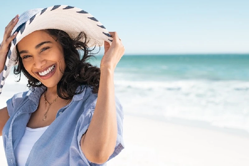Mujer mexicana sonriente disfrutando en la playa, imaginando su aventura en Egipto.