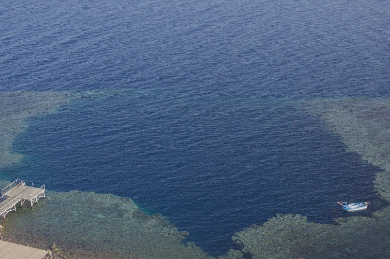 Fotografía aérea mostrando el icónico Blue Hole de Dahab y arrecifes circundantes en el Mar Rojo, Egipto.