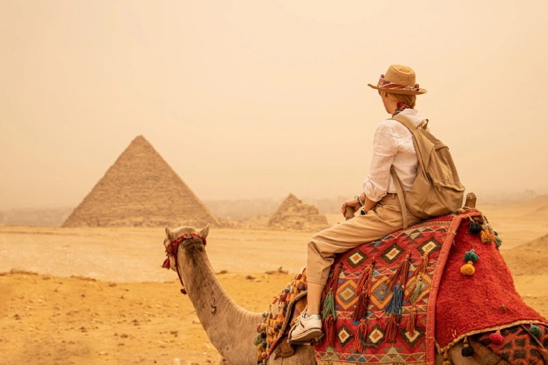 Pirámides de Guiza Una mujer turista montado un camello enfrente de las pirámides de Giza