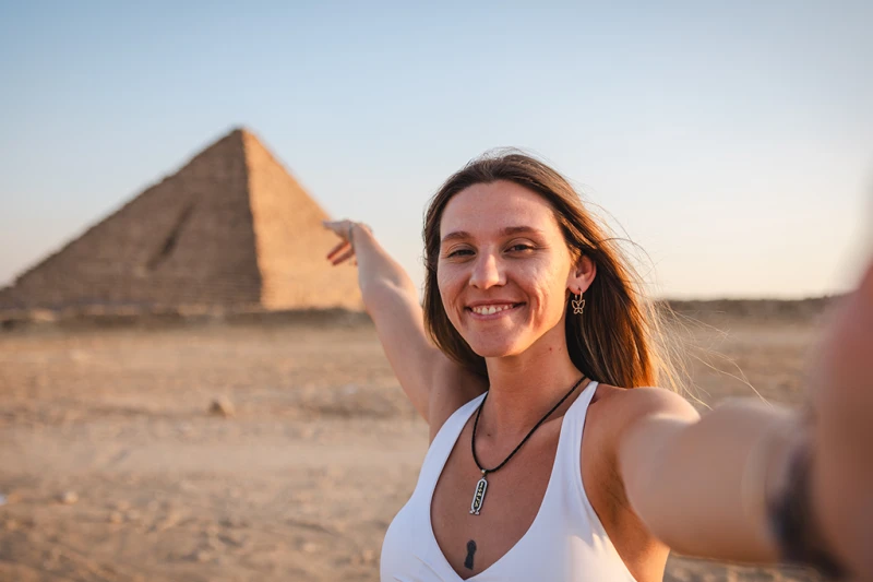 una mujer turista tomando selfie enfrente de la Pirámide de Kefrén