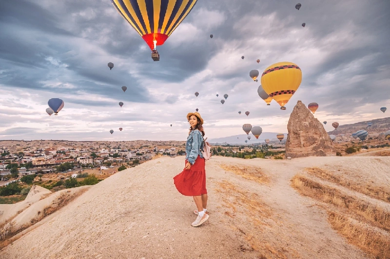 A tourist girl in Cappadocia amid floating hot air balloons.