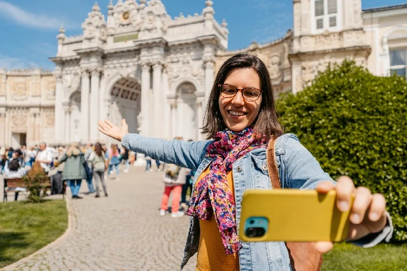 A tourist taking a selfie in front of Dolmabahçe Palace in Istanbul.