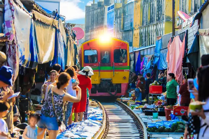 Maeklong Railway Market in Samut Songkhram, where vendors move their goods as the train passes.