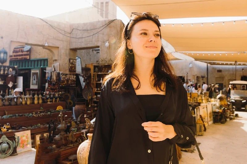 A smiling tourist soaking in the lively atmosphere of Dubai’s old town.