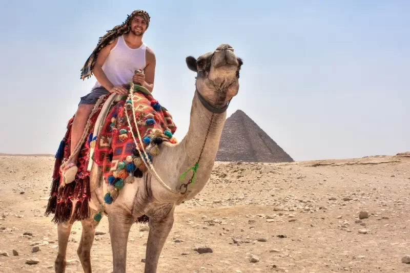 A traveler enjoying a camel ride with the Pyramids as a breathtaking backdrop