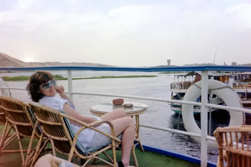 A traveler relaxing on board a Nile cruise while taking in the stunning river views