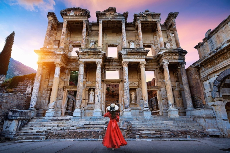 Female tourist in a red dress exploring Ephesus.