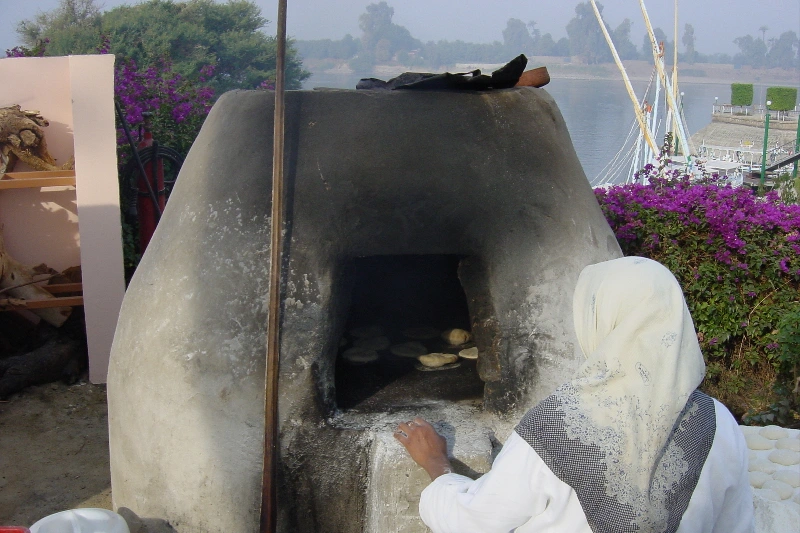 Mujer preparando pan tradicional egipcio en horno de arcilla