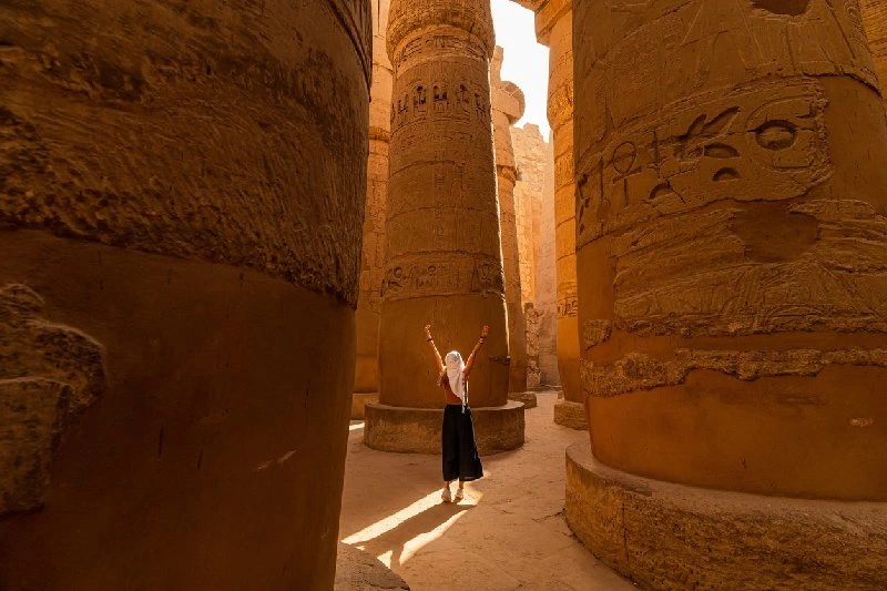 Persona entre las enormes columnas del Templo de Karnak con jeroglíficos en Luxor, Egipto.