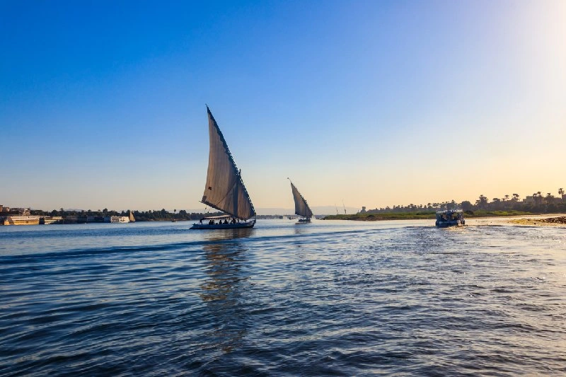 Falucas navegando por las aguas del río Nilo durante el atardecer en Egipto.