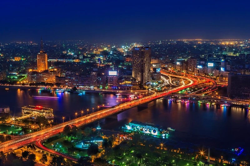 Vista aérea de El Cairo iluminado de noche con el río Nilo atravesando la ciudad.