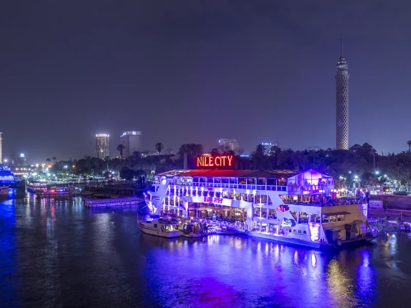 Bateau illuminé sur le Nil la nuit au Caire avec la tour du Caire en arrière-plan