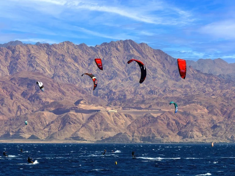 Kitesurfeurs aux voiles colorées sur la mer Rouge devant des montagnes désertiques
