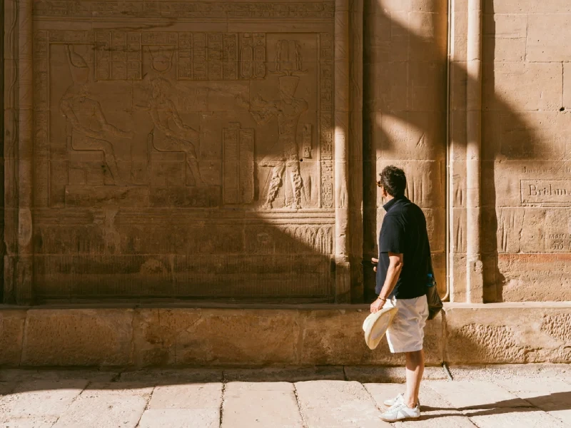 Voyageur longeant les bas-reliefs du temple de Philae à Assouan