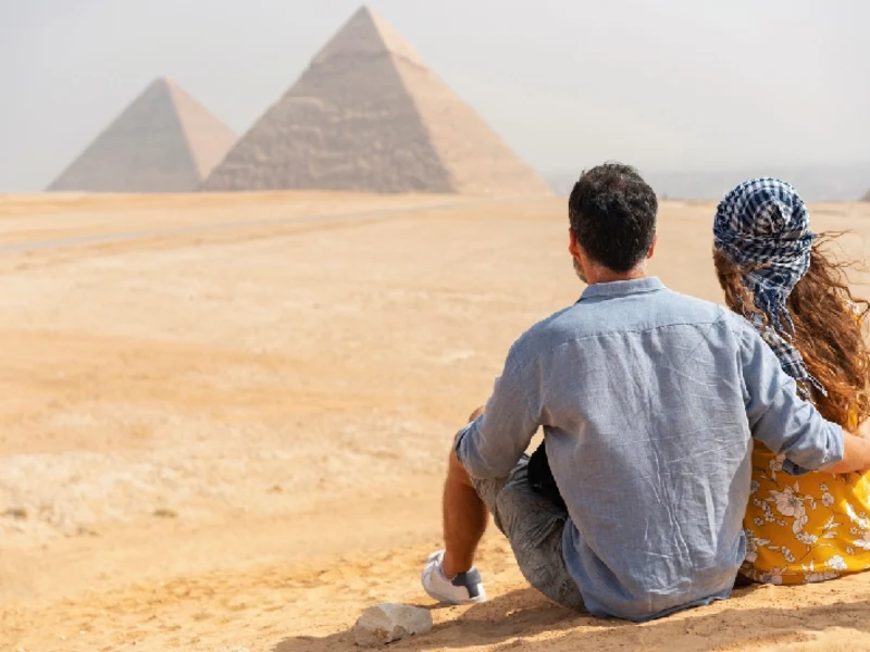Vista trasera de una pareja que viaja visitando las Pirámides de Giza en Egipto.