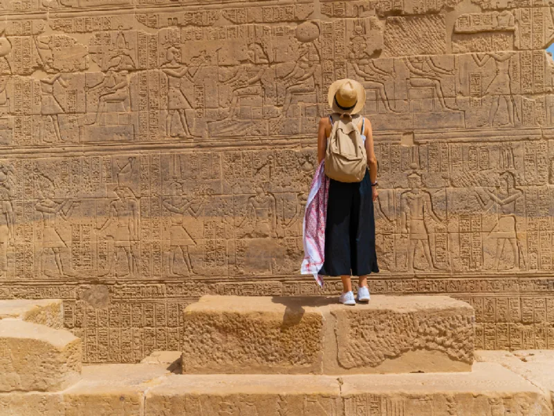 Mujer de pie frente al Templo de Filae, también conocido como Templo de Isis, en Asuán, Egipto.