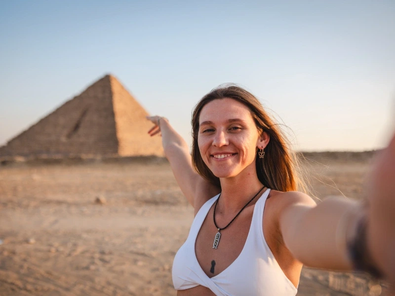 una giovane viaggiatrice cattura la magia del momento con un selfie davanti alle maestose Piramidi di Giza