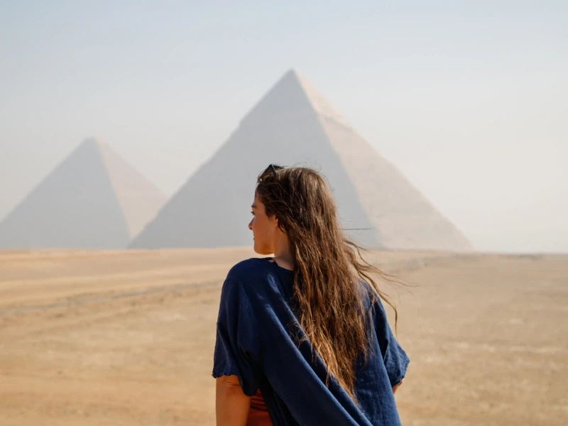 Giovane viaggiatrice ammira la vista panoramica sulle Piramidi di Giza durante un tour guidato in Egitto