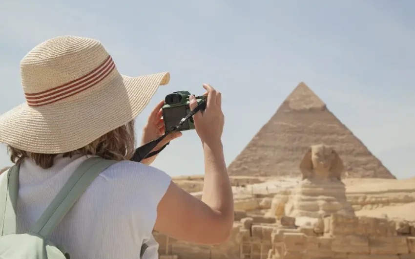 una donna scatta una foto per la piramide , dove andare in egitto a dicembre