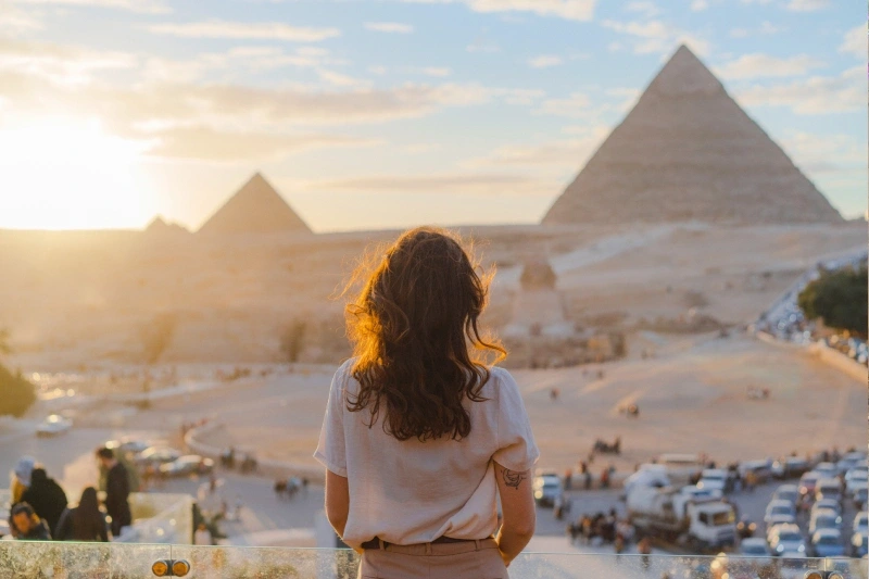 Donna in piedi sulla terrazza sullo sfondo delle piramidi di Giza, cosa vedere in egitto