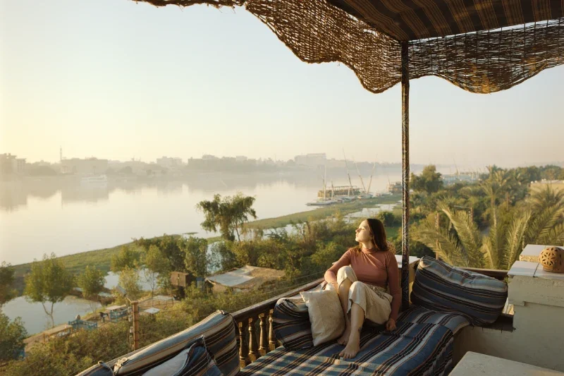Donna seduta sulla terrazza e guardando il Nilo al tramonto a Luxor, cosa vedere i egitto