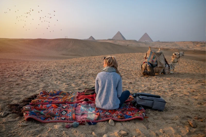 Donna guarda il tramonto alle Piramidi di Giza, pasqua in egitto