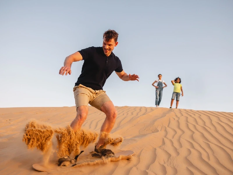 Man enjoying sandboarding in Dubai Man enjoying sandboarding in Dubai